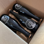 Three bottles of Dragon Des Alpes champagne in a cardboard box.