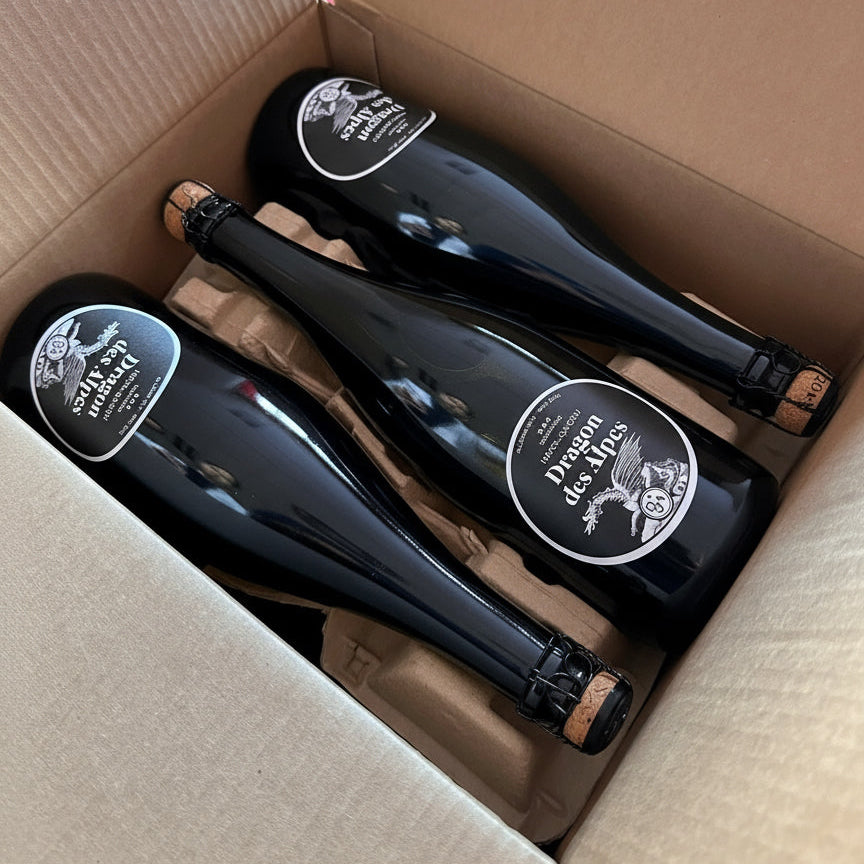 Three bottles of Dragon Des Alpes champagne in a cardboard box.